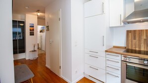 A modern kitchen with white cabinetry, a wooden countertop, and stainless steel appliances. - Ocean Club - Exklusive Ferienwohnung: mit Balkon, Direktem Ostseeblick & Strandzugang (Timmendorfer Strand)