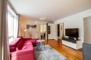 Un salon moderne avec un canapé rouge, un téléviseur et un plancher en bois.