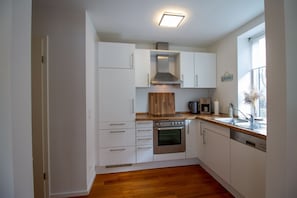 Une cuisine moderne avec des armoires blanches, un four en acier inoxydable et un plan de travail en bois.