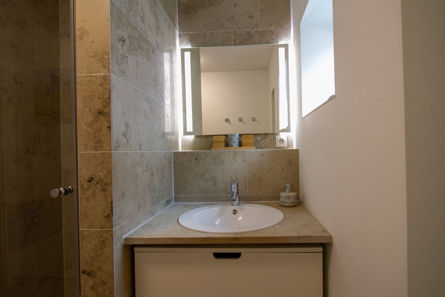 Een badkamer met een wit wastafel, een spiegel en een toilet.