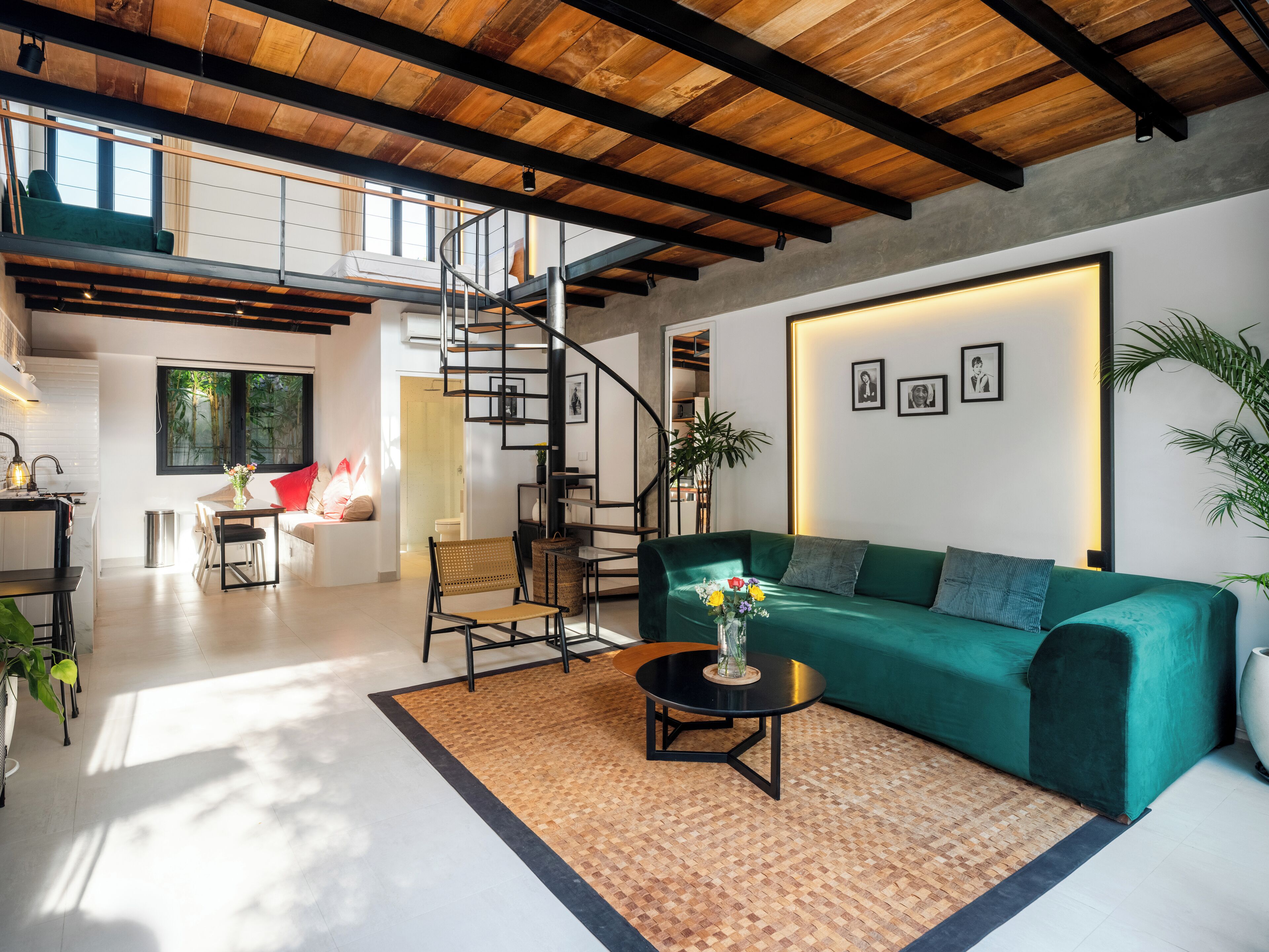A modern living room with a green sofa, a round coffee table, and a staircase leading to an upper level.
