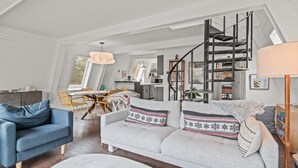 Un vaste espace de vie comprenant un canapé, une table à manger et un escalier.