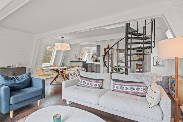 A spacious living area with a sofa, a dining table, and a staircase.