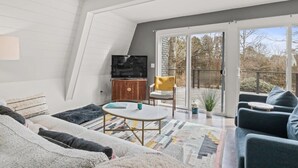 Un intérieur comprenant un canapé, une table basse, un téléviseur et un balcon avec vue.