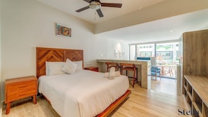 A spacious bedroom with a large bed, wooden headboard, and a ceiling fan. - Stylish Playa Condo: Rooftop Pool, Gym, Near Beach (Playa del Carmen)