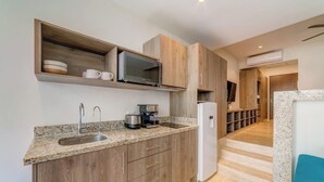 A modern kitchen with granite countertops, wooden cabinets, a built-in microwave, and a coffee maker. - Stylish Playa Condo: Rooftop Pool, Gym, Near Beach (Playa del Carmen)