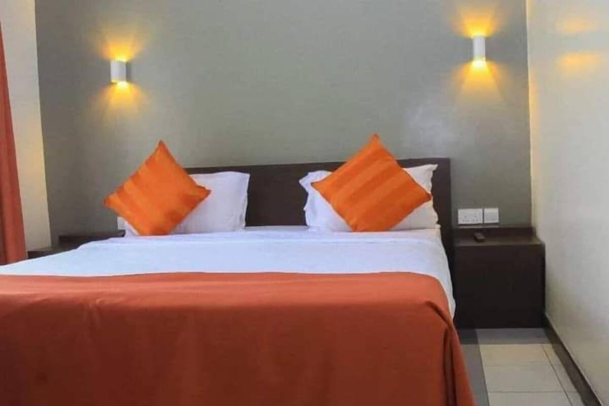 A hotel room with a bed, two nightstands, and two wall-mounted lights.