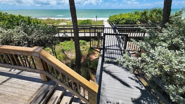 Eine Holzterrasse mit Blick auf den Ozean und den Strand.