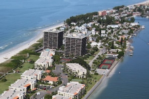 An aerial view of a coastal area with high-rise buildings, a beach, and a marina.