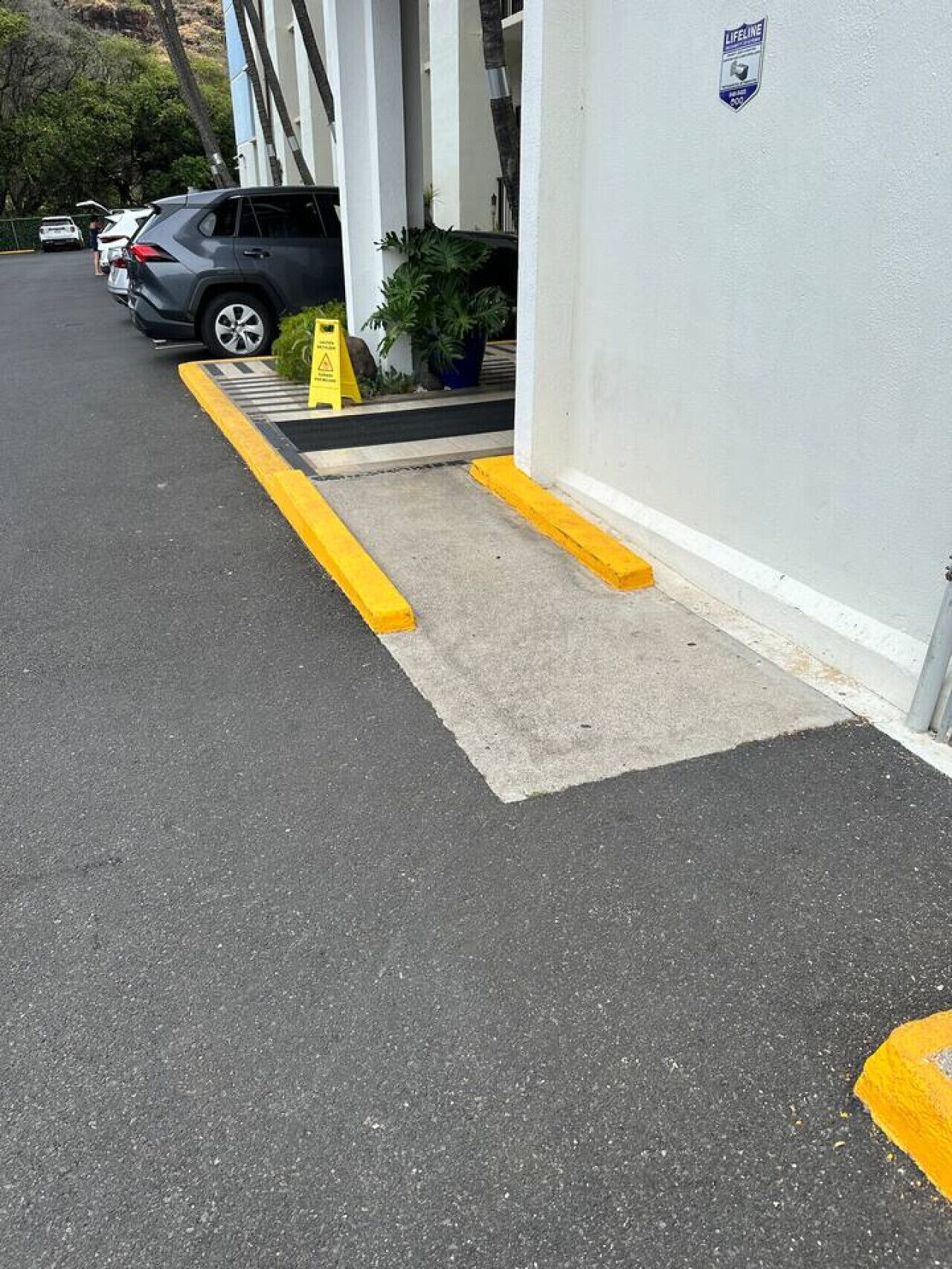 A parking area with a yellow curb and a concrete ramp leading to a building entrance.