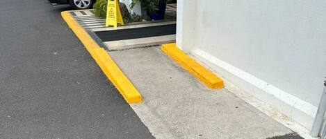 A parking area with a yellow curb and a concrete ramp leading to a building entrance.