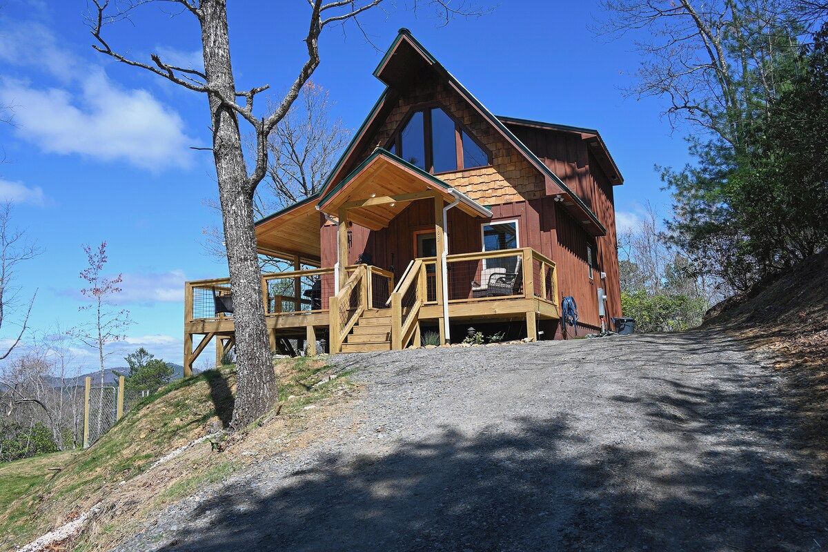 A wooden cabin with a balcony, a covered porch, and a view of the surrounding landscape.