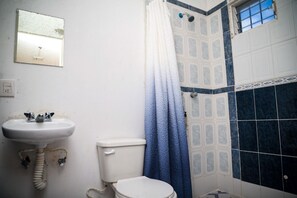 A bathroom with a white sink, a toilet, and a shower with a blue curtain.