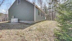 A single-story house with a sloped roof, a small attached garage, and a generator on the ground. - Steps to Lake Access! Eastbrook Family Cabin (Eastbrook)