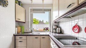 A kitchen with a window, cabinets, a sink, and a stove. - Apartment 'Ferienwohnung Flensburg Mürwik' with Shared Garden, Balcony and Wi-Fi (Flensburg)