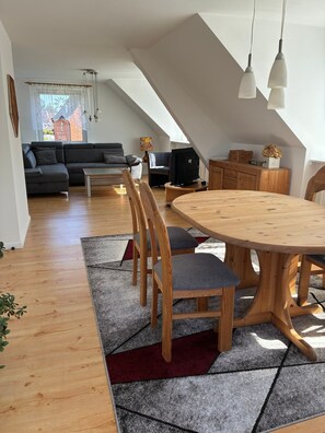 A modern loft-style living space with a dining area, lofted ceiling, and a view of the outside. - Apartment 'Ferienwohnung Flensburg Mürwik' with Shared Garden, Balcony and Wi-Fi (Flensburg)