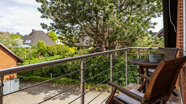 A balcony with a metal railing, a wooden chair, and a table with a potted plant. - Apartment 'Ferienwohnung Flensburg Mürwik' with Shared Garden, Balcony and Wi-Fi (Flensburg)
