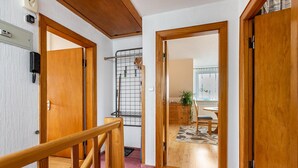 A hallway with wooden doors, a staircase, and a kitchen area visible through an open door. - Apartment 'Ferienwohnung Flensburg Mürwik' with Shared Garden, Balcony and Wi-Fi (Flensburg)