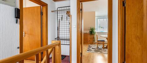 A hallway with wooden doors, a staircase, and a kitchen area visible through an open door.