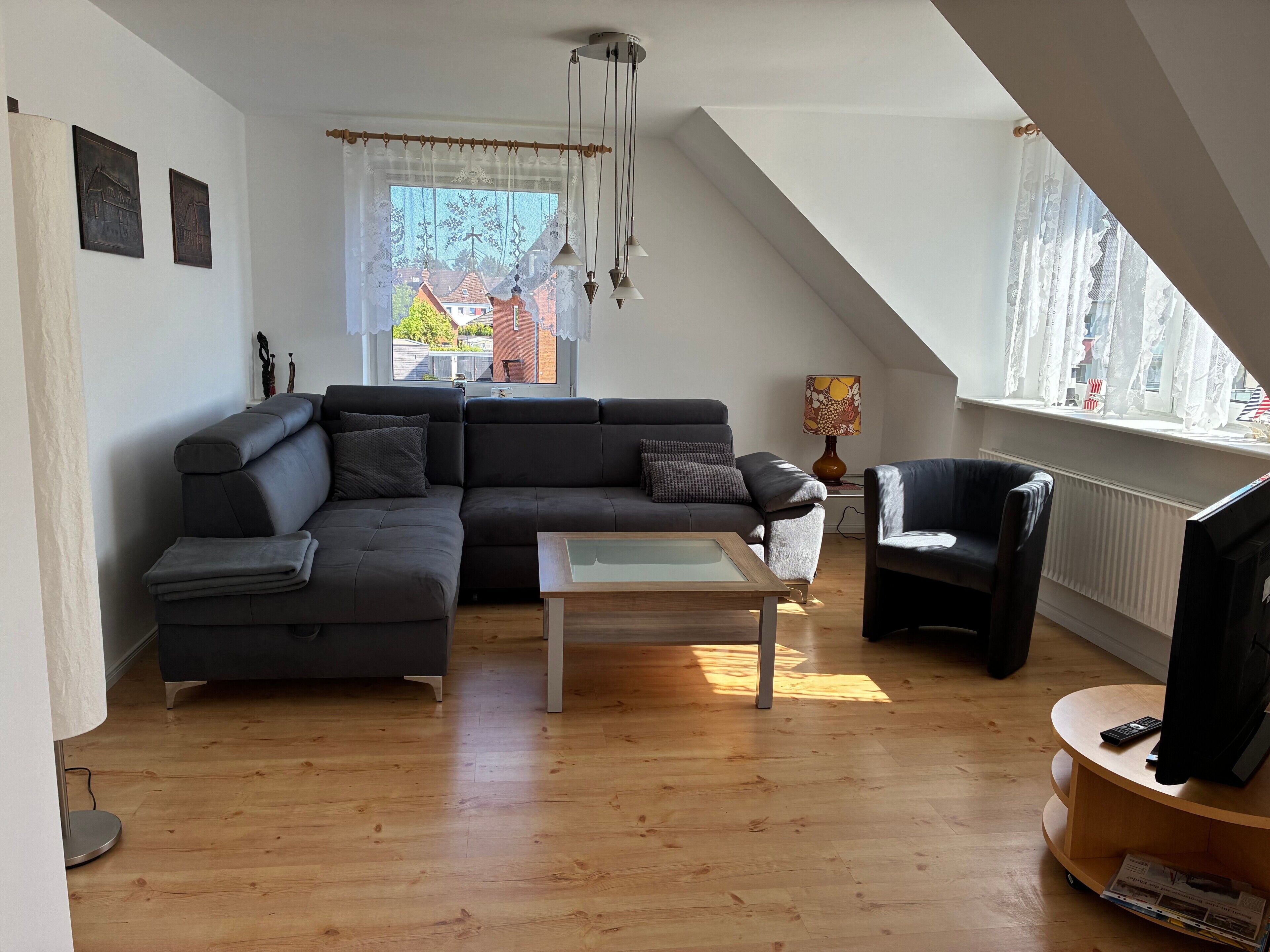 A modern living room with a sectional sofa, a coffee table, a TV, and a window with curtains.