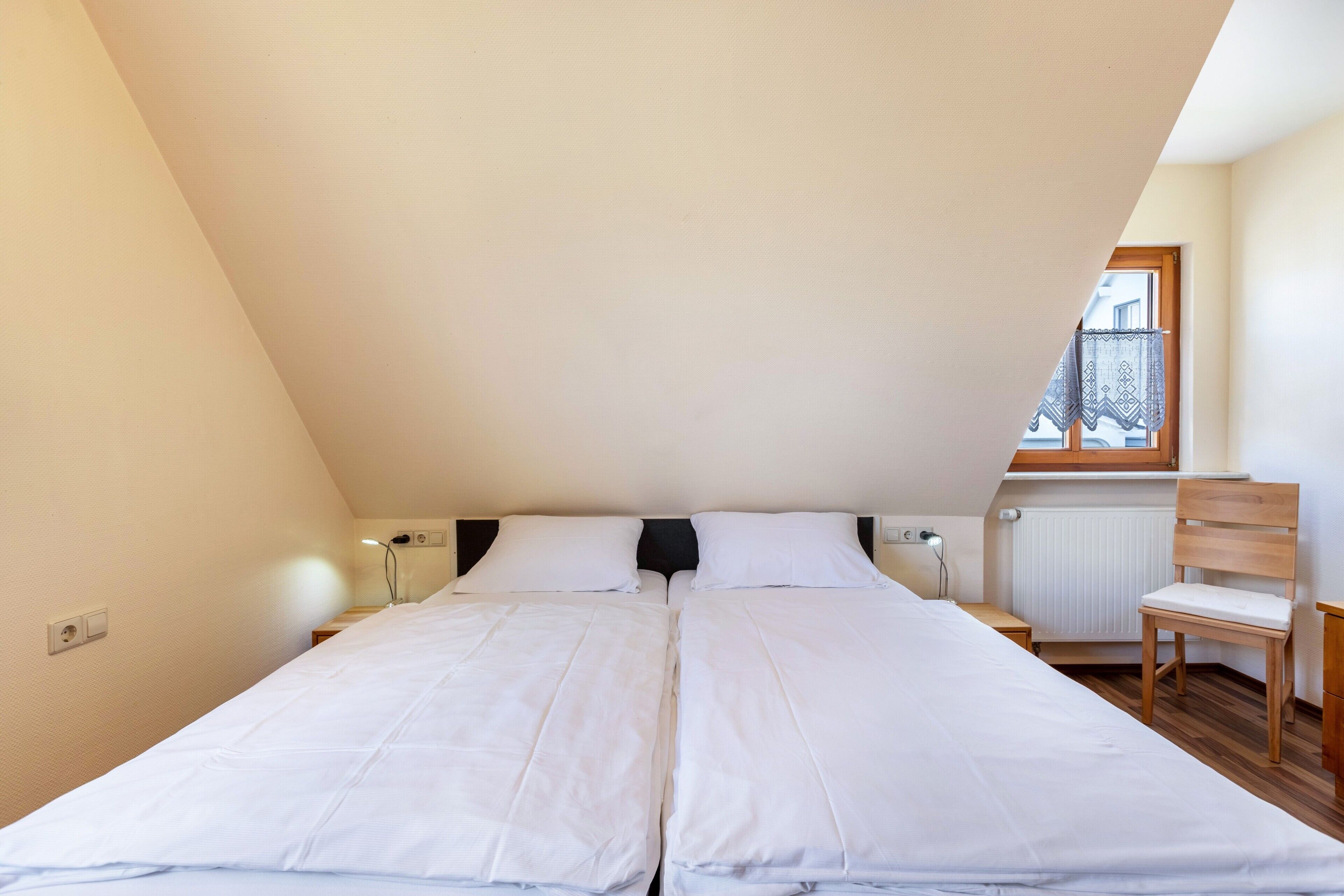 A bedroom with a large bed, a chair, a window, and a radiator.