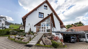 A two-story house with a sloped roof, a front porch, and a garage. - Holiday Apartment "Dachspitz - Junges Wohnen" with Shared Garden & Wi-Fi (Unterkirnach)