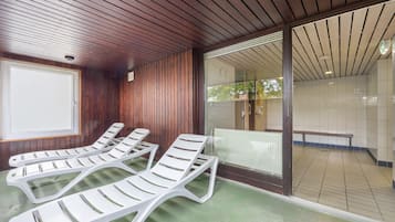 Ein Zimmer mit Holzvertäfelung, einem grünen Boden und einer Schiebeglastür, die zu einem Außenbereich mit einer Bank führt.