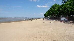 Ein Strand mit sandigem Ufer, einer Wandmalerei an der Klippe und einem klaren Himmel.