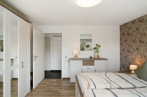 Ein Schlafzimmer mit Bett, Nachttisch, Lampe und einem Bild an der Wand.