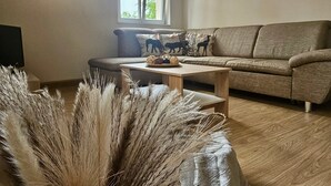 Een woonkamer met een bank, een salontafel en een raam met natuurlijk licht.