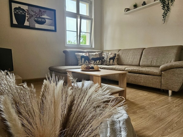 A living room with a sofa, a coffee table, and a window with natural light.