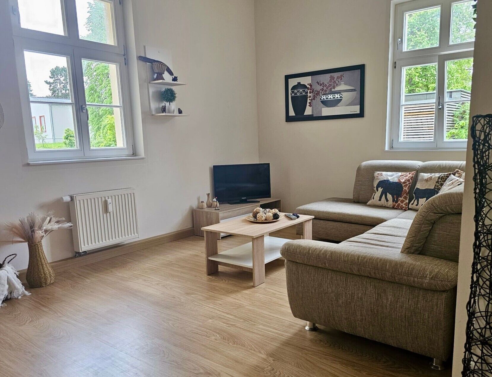 Ein Wohnzimmer mit Sofa, Fernseher, Couchtisch und Heizkörper.