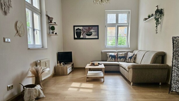 Een woonkamer met een bank, een salontafel, een televisie en een raam.