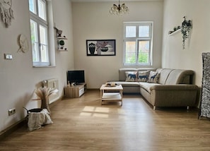 A living room with a sofa, a coffee table, a TV, and a window.