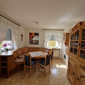 A dining area with a round table, wooden chairs, a bench, and a cabinet with glass doors.