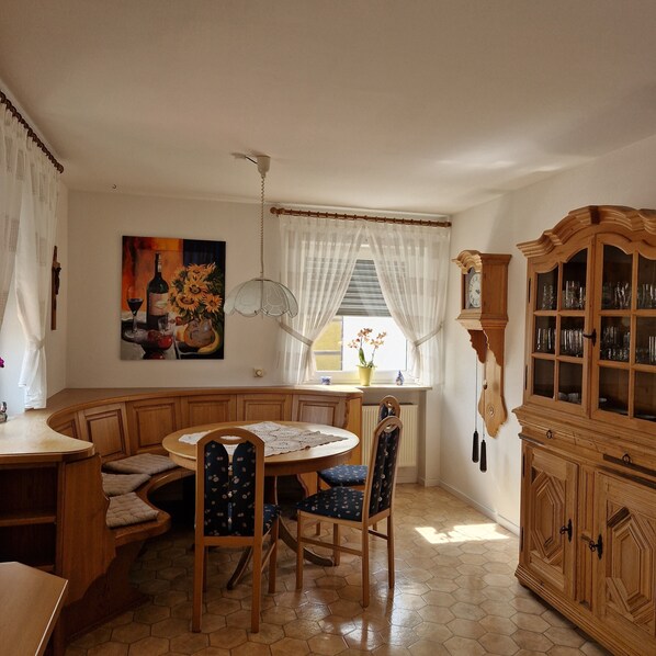 A dining area with a round table, chairs, a cabinet with glass doors, and a painting on the wall.