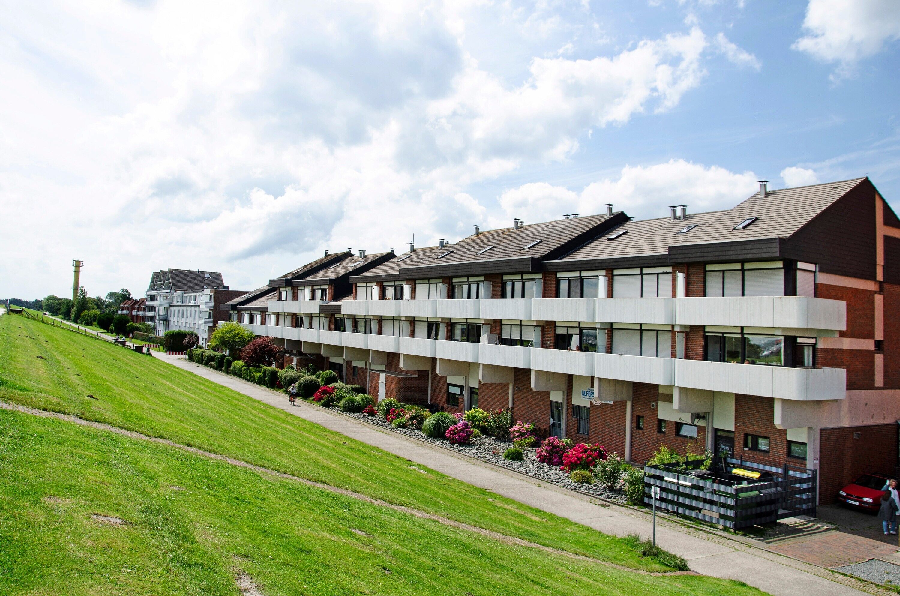 A row of modern residential buildings with a green lawn in the foreground.
