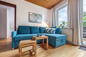 Un salon avec un canapé bleu, une table basse en bois et une carte du monde accrochée au mur.