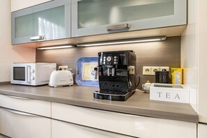 Une cuisine équipée d’une machine à café, d’un four à micro-ondes, d’un grille-pain et d’une sélection de thés.