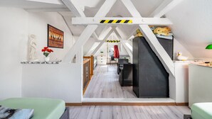 Une chambre mansardée avec un plafond en pente, un lit, un bureau et une chaise.