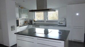 A modern kitchen with white cabinets, a large island with a black countertop, and a window above the sink.