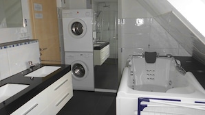 A hotel bathroom with a sink, a washing machine, a shower, and a bathtub. - Apartment 'Stuifenblick' with Mountain View, Private Garden and Wi-Fi (Waldstetten)