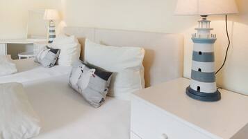 Ein Hotelzimmer mit einem Bett, Kissen, einem Nachttisch, einer Lampe und einer dekorativen Leuchtturm-Lampe.