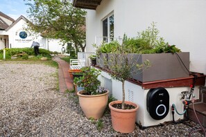 L’entrée d’un hôtel, avec un chemin de gravier, des plantes en pot et un élément décoratif aquatique.