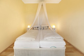 A double bed with a canopy, bedside lamps, and a wicker base. - Apartment 'Wohnung 2' with Private Terrace, Shared Garden and Wi-Fi (Hohwacht (Ostsee))