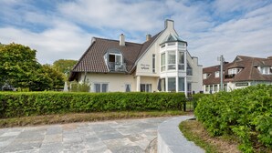 Ein zweistöckiges Haus mit Balkon, Wintergarten und befestigter Auffahrt.