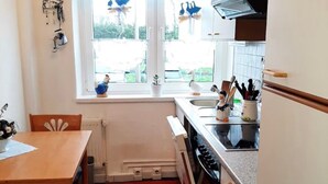 Una cocina compacta con ventana, una mesa de comedor y una alfombra roja.