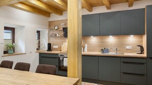 Une cuisine moderne avec des poutres en bois, un coin repas comprenant une table et des chaises, et des placards intégrés.