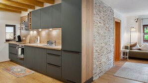 Une cuisine moderne avec des armoires grises, un plafond en bois et un mur d’accent en briques.