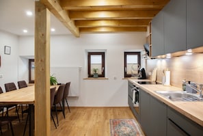 A modern kitchen with wooden beams, a dining area with a table and chairs, and a small window with a plant. - Apartment 'Ferienwohnung Waldzauber' with Sea View, Shared Terrace and Wi-Fi (Oetz)